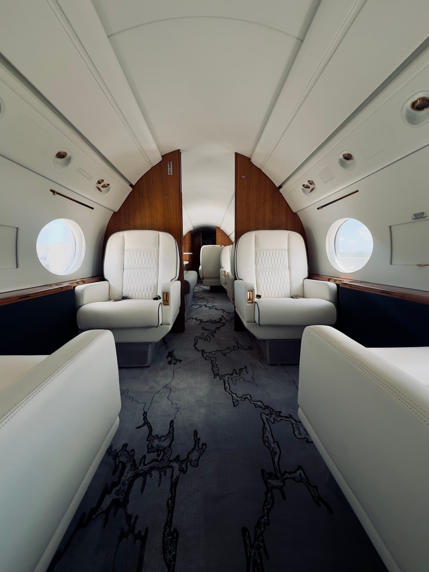 Cabina de un jet privado con butacas de cuero blanco y paneles de madera