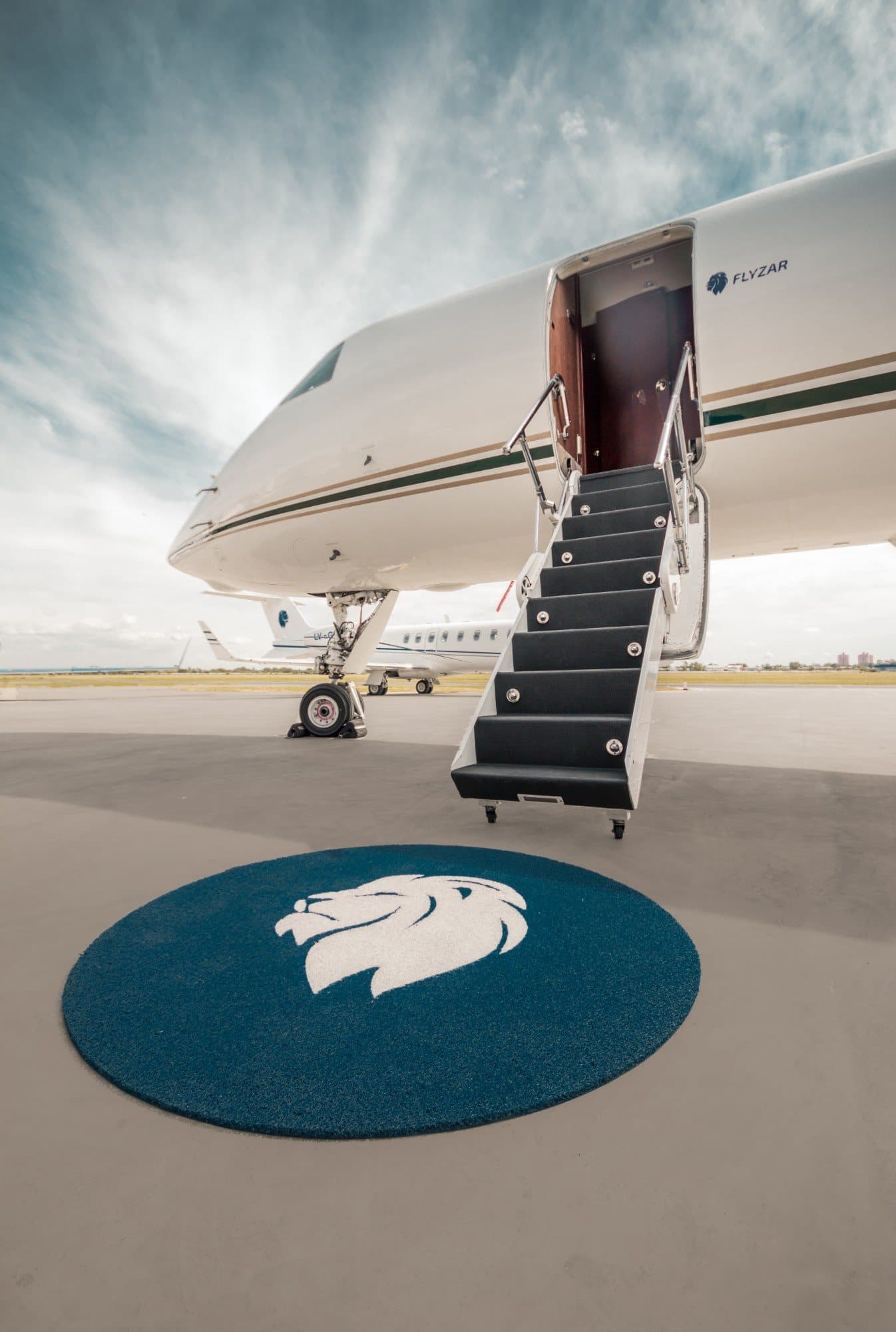 Escalerilla de un jet privado sobre la alfombra con el león de Flyzar